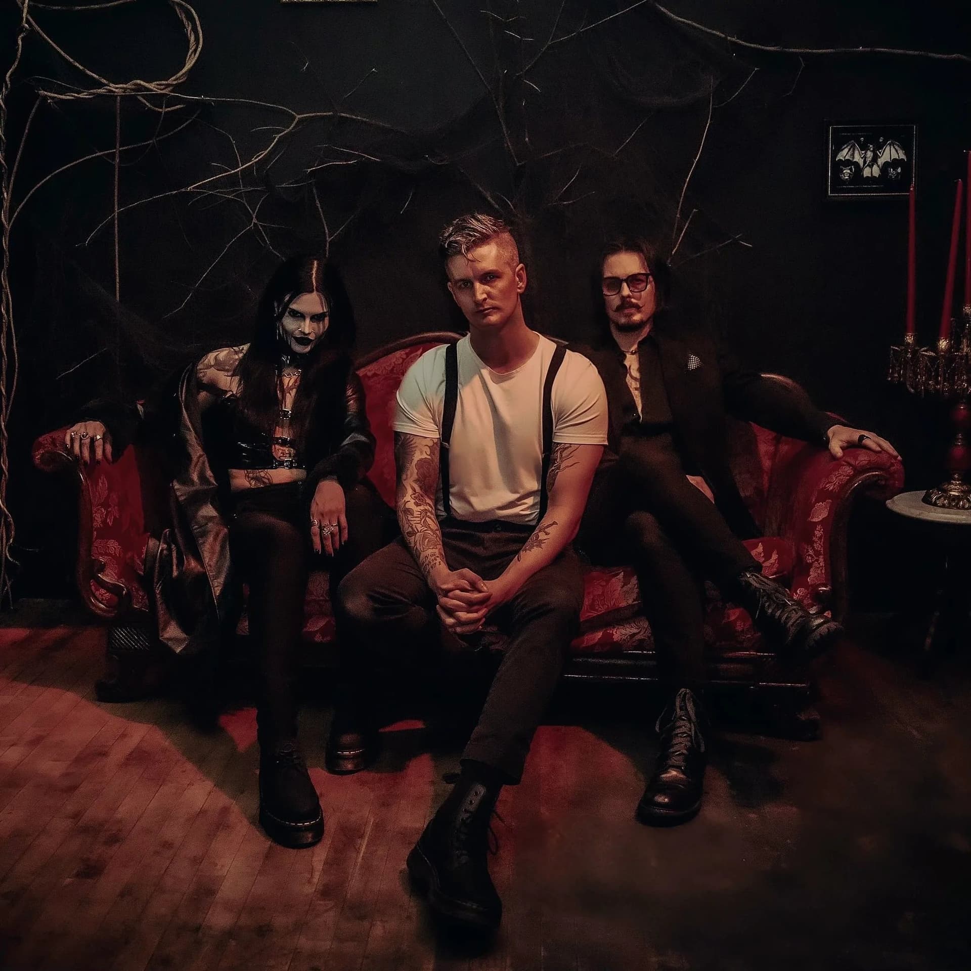 Circuit Preacher, three members on a red velvet sofa in a dark, candle-lit room
